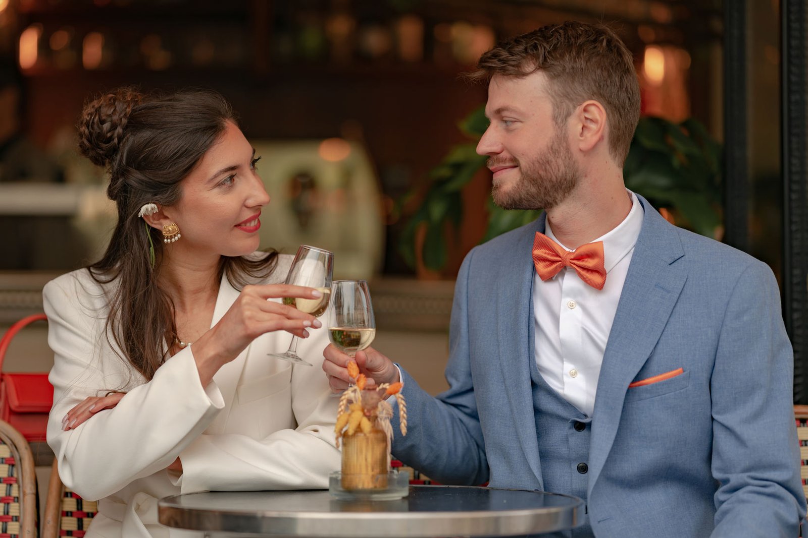 Mariage de printemps à Paris. Photo de mariage d'un couple qui trinque avec une coupe de champagne sur une terrasse à Paris