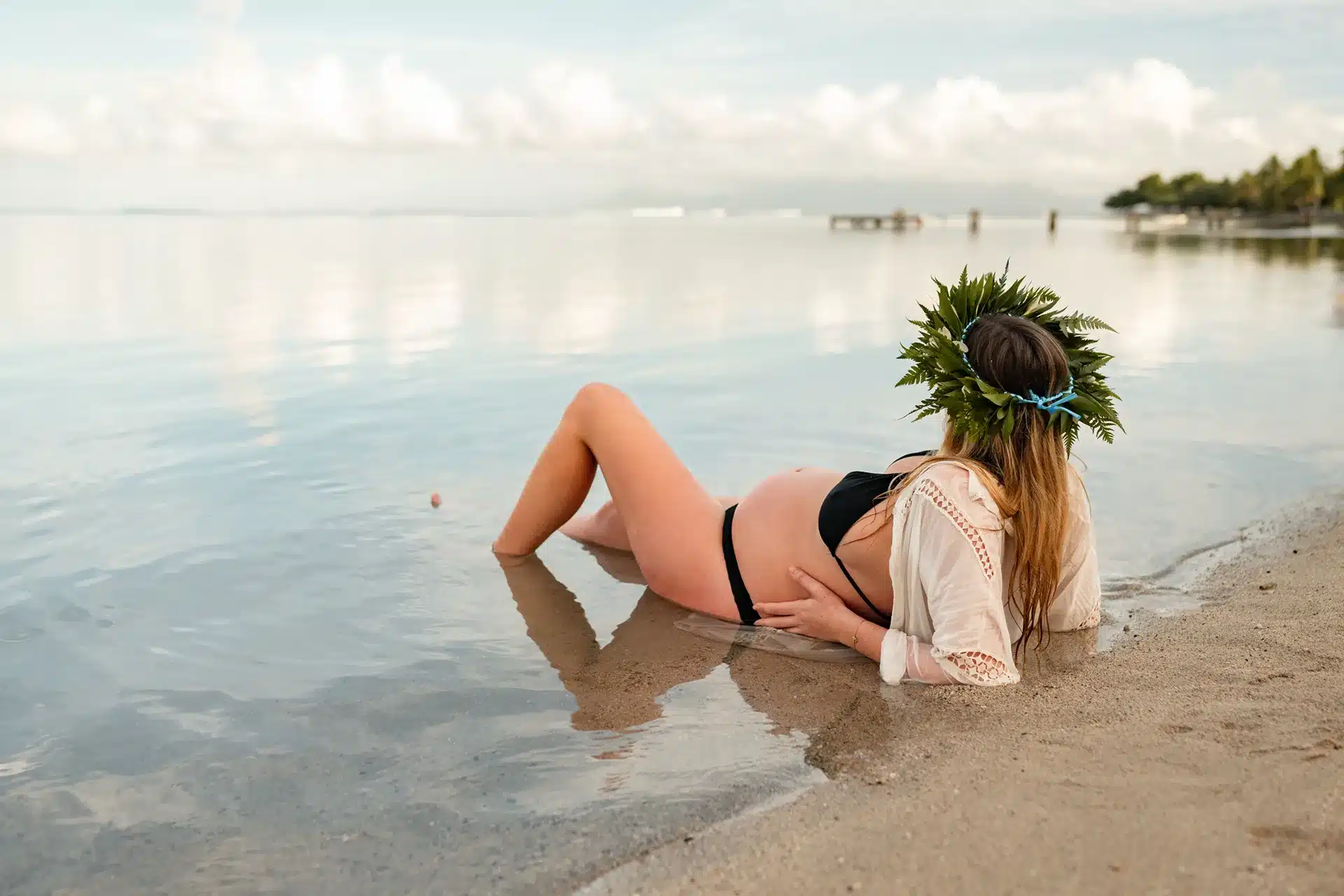 Shooting grossesse à Tahiti avec une future maman allongée sur la plage de Toaroto