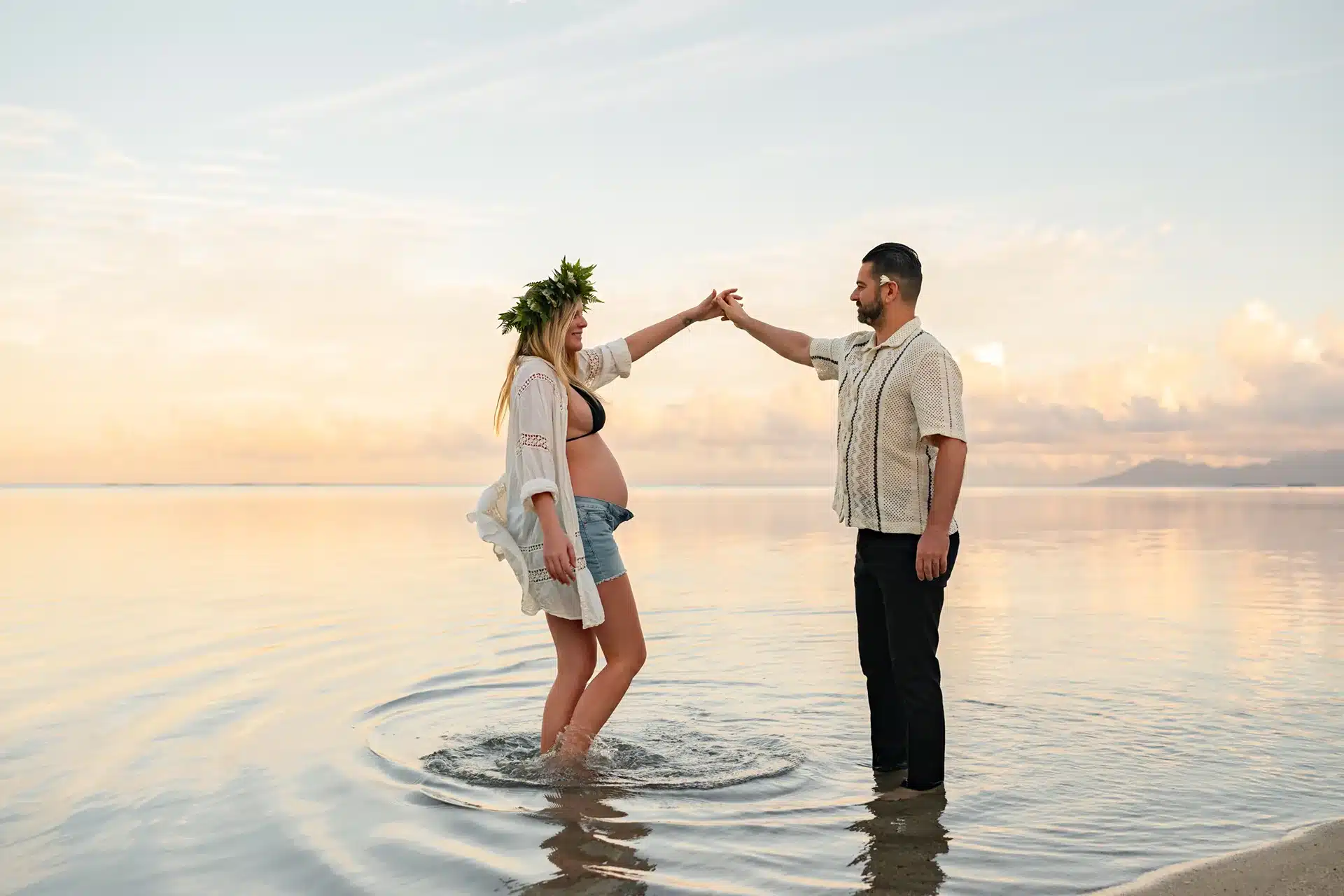 Shooting grossesse à Tahiti avec de futurs parents qui marchent dans l'eau