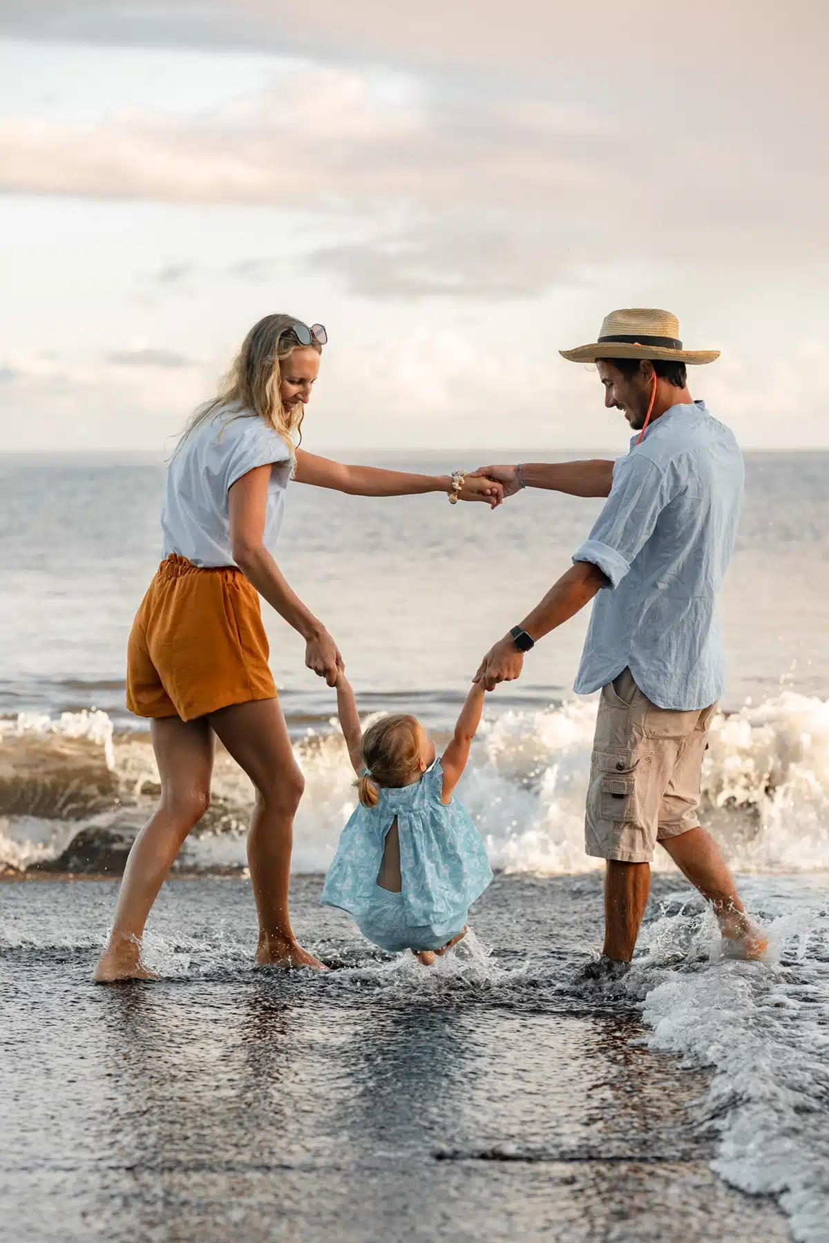 Une famille qui danse sur la plage les pieds dans l'eau, prise par une photographe à Tahiti et Moorea